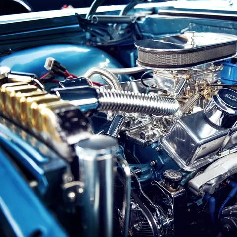 A detailed car engine bay with chrome parts and blue wiring